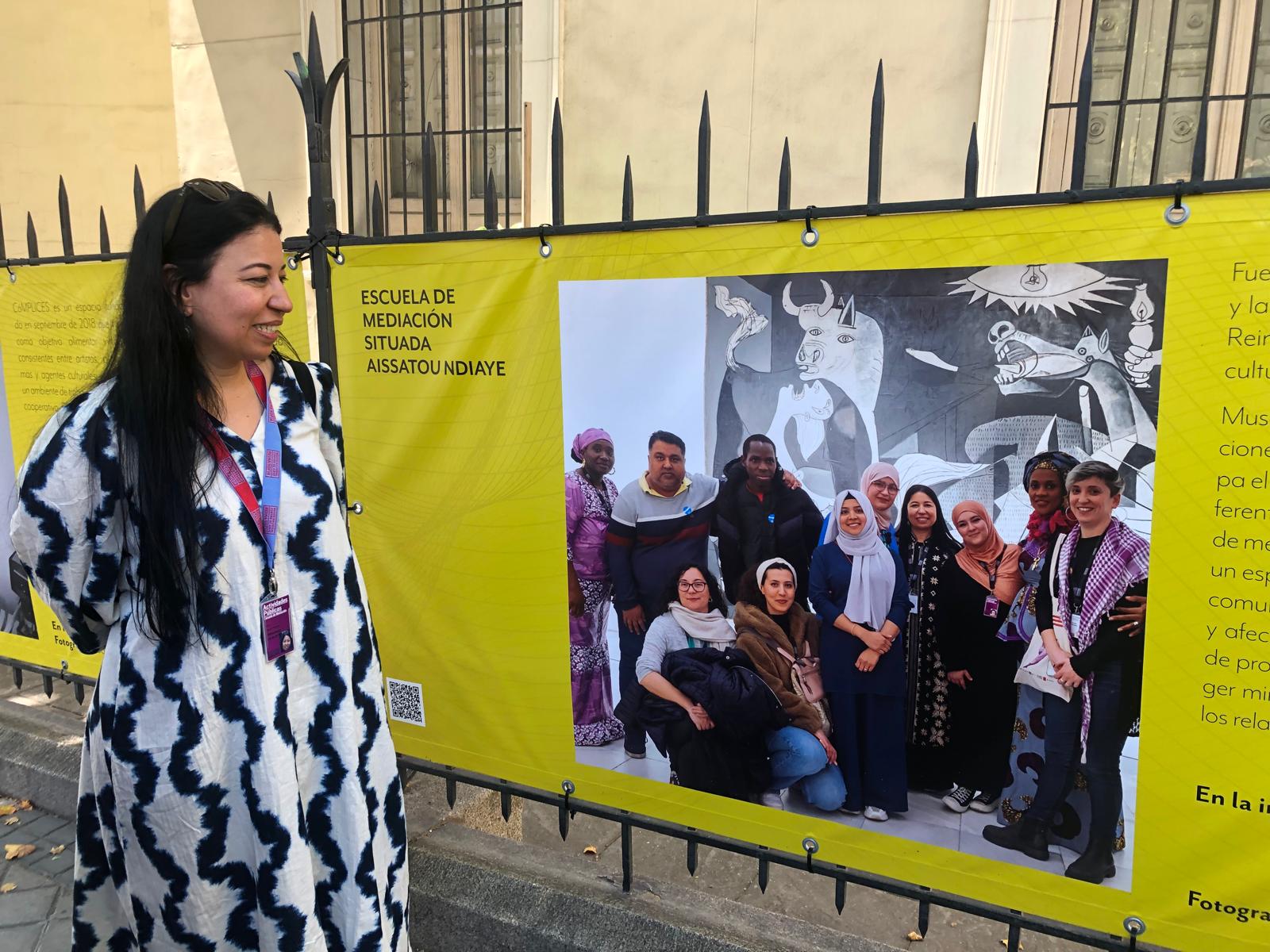 La mediadora intercultural Hanan Dalouh Amghar viendo la foto de la Escuela de Mediación situada Aissatou Ndiaye en nuestra exposición Migración&Cultura en el Museo Nacional de Antropología. Madrid, junio